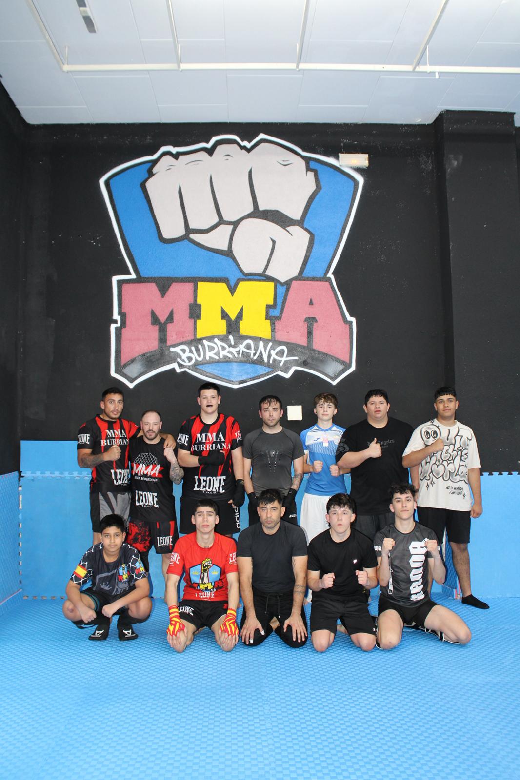 El grupo de MMA Burriana ante el mural del gimnasio